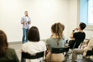 Une personne debout en train de parler devant un public attentif, illustrant l’art de la communication efficace.