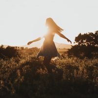 Femme dansant dans un champ, reconnectée à elle-même après un coaching.