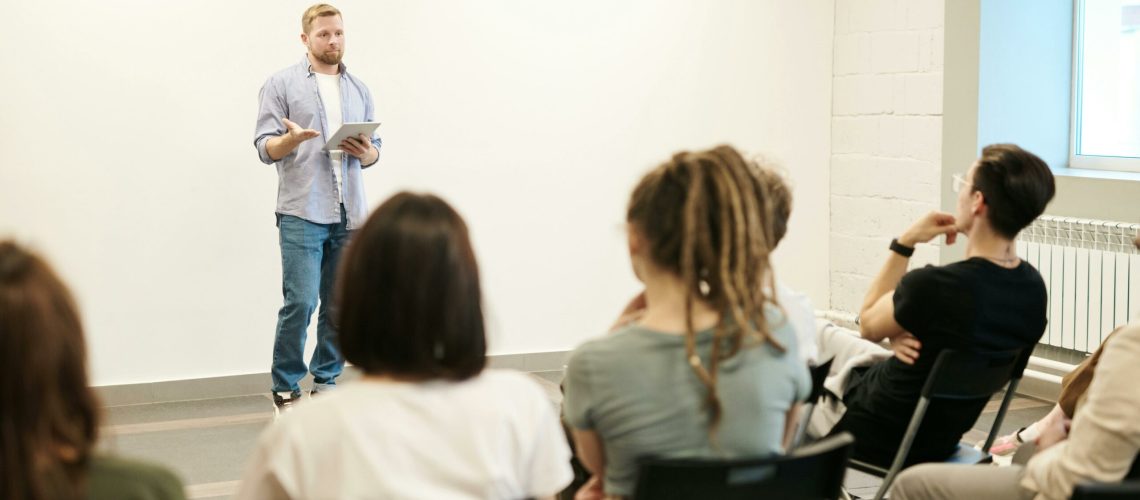 Une personne debout en train de parler devant un public attentif, illustrant l’art de la communication efficace.